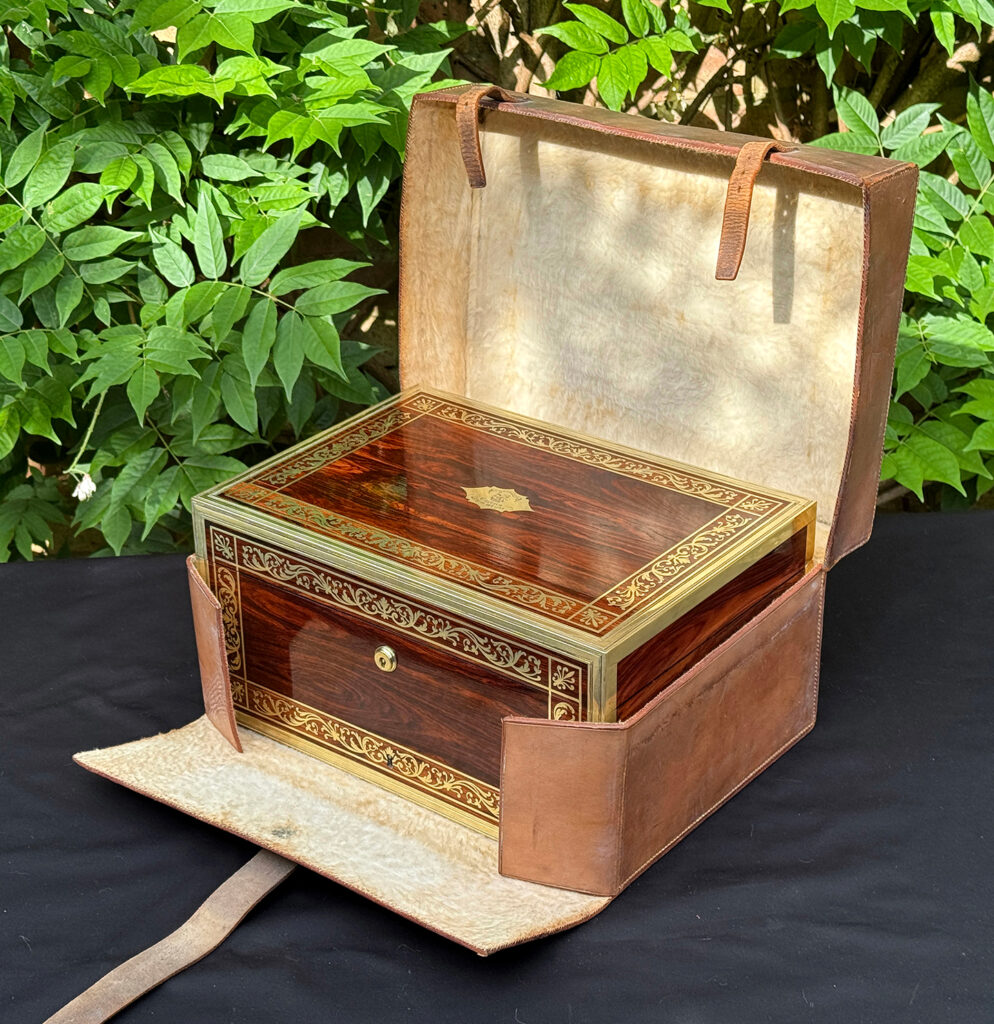 Front right view of an antique jewellery box in kingwood, by Wells & Lambe, in its outer leather case.