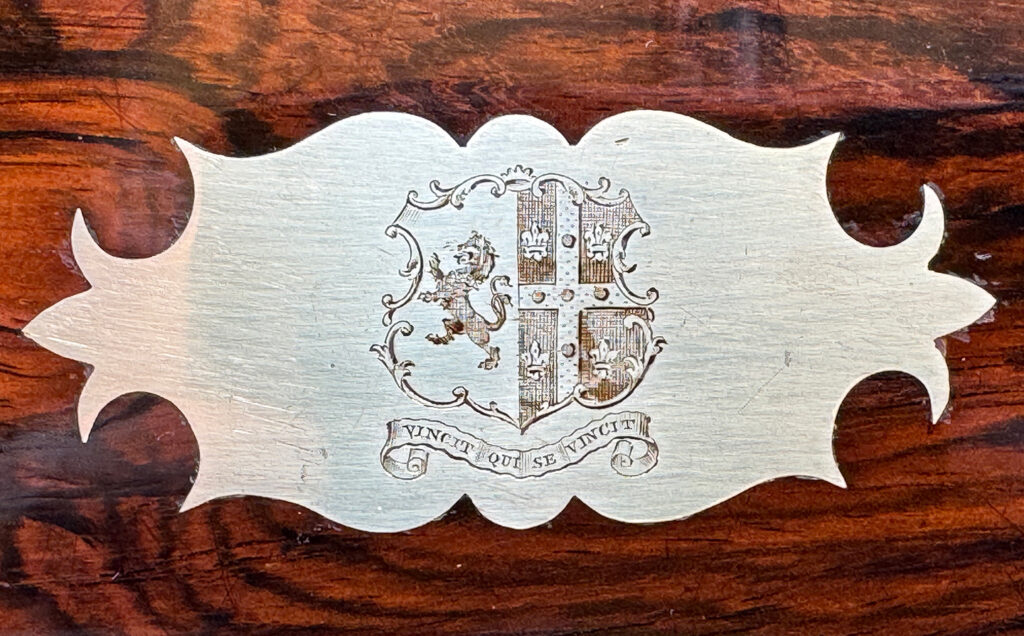 Close up of the engraved family crest and motto from an antique document box in rosewood with satinwood interior, by Leuchars.