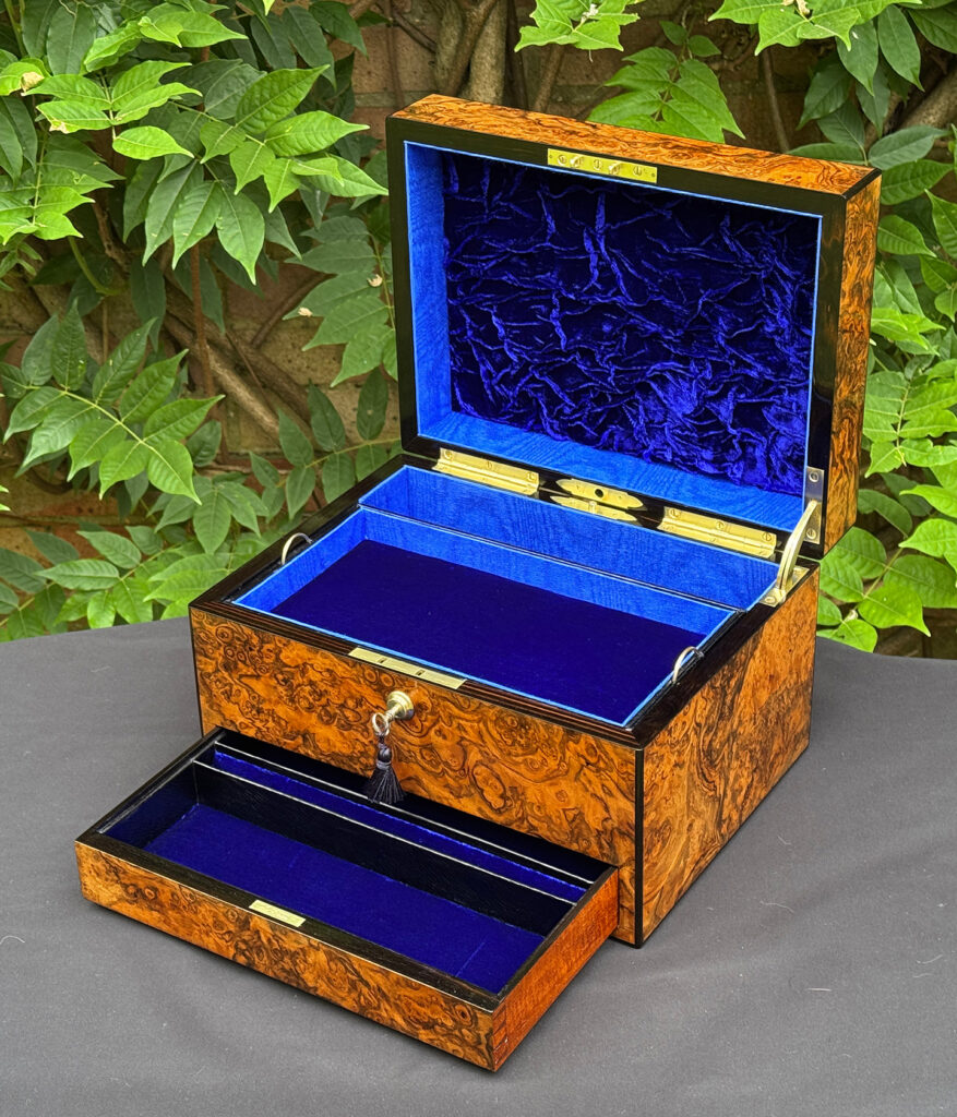 Front right interior view of an antique jewellery box in burr walnut, by George Betjemann & Sons, with lower drawer opened.